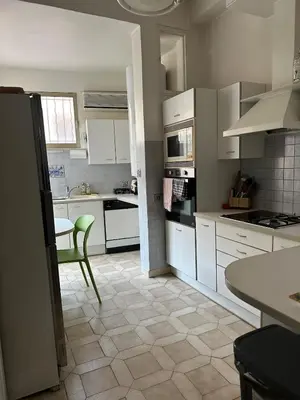 a kitchen with white cabinets and a green chair in it at T3 Cannes Banane in Cannes