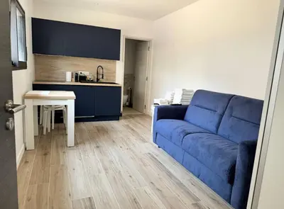 a living room with a blue couch and a kitchen at Studios Cannes Les 3 éléments in Cannes