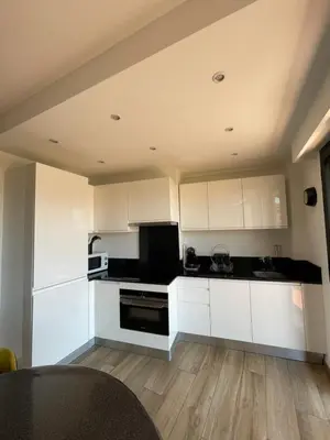 a kitchen with white cabinets and a black appliances at 2 pièces vue sur le Suquet in Cannes