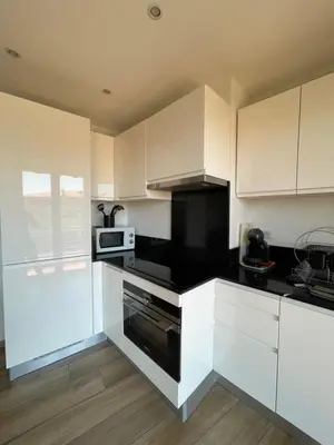 a kitchen with white cabinets and black counter tops at 2 pièces vue sur le Suquet in Cannes
