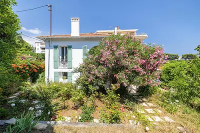 a house with a flowering bush in front of it at LA VILLA DES FLEURS en duplex avec jardin et piscine in Le Cannet