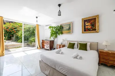 a bedroom with a large bed and a large window at LA VILLA DES FLEURS en duplex avec jardin et piscine in Le Cannet