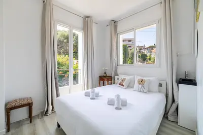 a white bedroom with a large white bed and windows at LA VILLA DES FLEURS en duplex avec jardin et piscine in Le Cannet