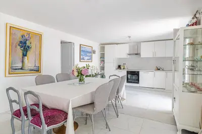 a kitchen and dining room with a white table and chairs at LA VILLA DES FLEURS en duplex avec jardin et piscine in Le Cannet