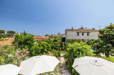 a couple of white umbrellas in a garden at LA VILLA DES FLEURS en duplex avec jardin et piscine in Le Cannet