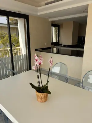 a white table with a vase with pink flowers on it at Appart exceptionnel terrasse mer in Cannes