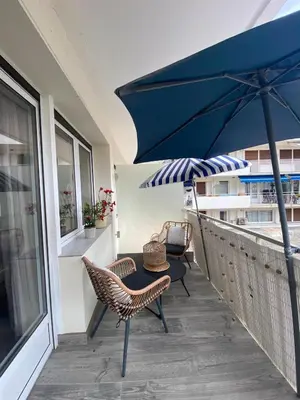 a patio with a table and a blue umbrella at Pretty flat in Cannes
