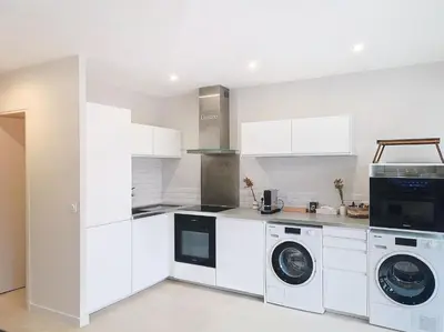 a kitchen with white cabinets and a washer and dryer at Appartement terrasse Cannes Suquet proche plage et centre in Cannes