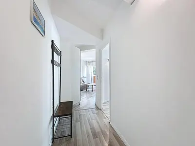 a white hallway with a mirror and a chair at Rivieira - By Coco in Cannes