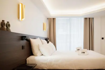 a bedroom with a white bed with a large window at 2 Appartements porte à porte Groupe & famille in Cannes