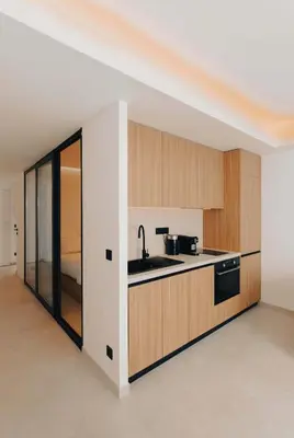 a kitchen with wooden cabinets and a sink in a room at 2 Appartements porte à porte Groupe & famille in Cannes