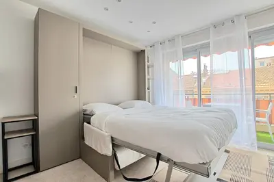 a bedroom with a bed and a large window at Studio lumineux avec parking - Gare & Palais à pied in Cannes