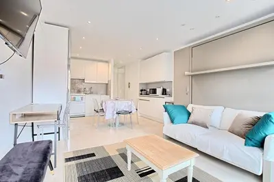 a living room with a white couch and a table at Studio lumineux avec parking - Gare & Palais à pied in Cannes