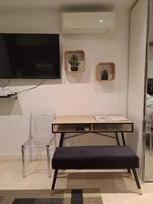 a table with a chair and a television on a wall at Studio lumineux avec parking - Gare & Palais à pied in Cannes