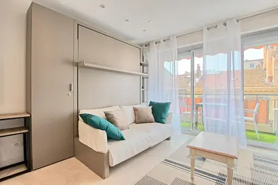 a living room with a couch and a large window at Studio lumineux avec parking - Gare & Palais à pied in Cannes