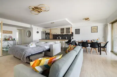 a living room with a bed and a couch and a kitchen at Reine Astrid Palm Beach Suite in Cannes