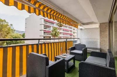 a balcony with chairs and tables and a building at Reine Astrid Palm Beach Suite in Cannes