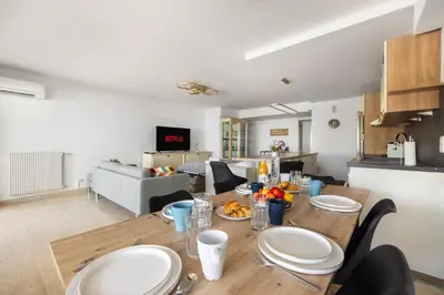 a kitchen and living room with a wooden table with plates on it at Reine Astrid Palm Beach Suite in Cannes