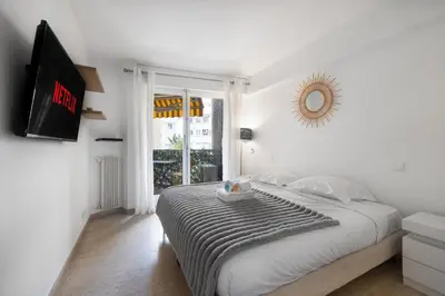 a white bedroom with a bed and a mirror at Reine Astrid Palm Beach Suite in Cannes
