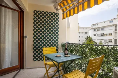 a table and chairs on a balcony with a window at Reine Astrid Palm Beach Suite in Cannes