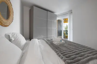 a white bedroom with a large bed with a mirror at Reine Astrid Palm Beach Suite in Cannes