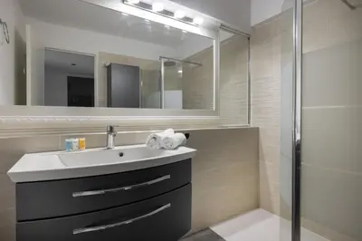 a bathroom with a sink and a shower at Reine Astrid Palm Beach Suite in Cannes