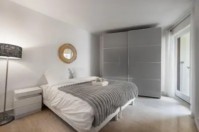 a white bedroom with a large bed and a mirror at Reine Astrid Palm Beach Suite in Cannes