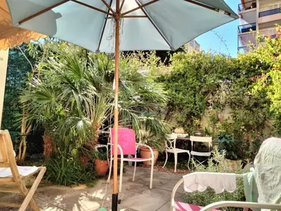 a patio with an umbrella and chairs and tables at Near Croisette atypic studio garden pool in Cannes