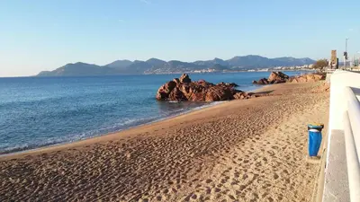 a sandy beach with rocks in the water at Beau studio à 5 min de la plage in Cannes