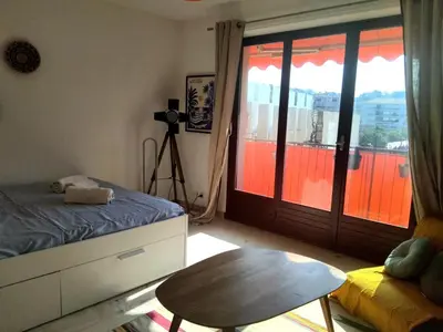 a bedroom with a bed and a table and a door at Beau studio à 5 min de la plage in Cannes