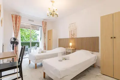 a bedroom with two beds and a table and a couch at Magnifique appartement proche plages et palais in Cannes