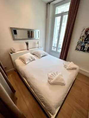 a bedroom with a bed with white sheets and a window at T2 coeur de Cannes a 2 pas de la croisette in Cannes