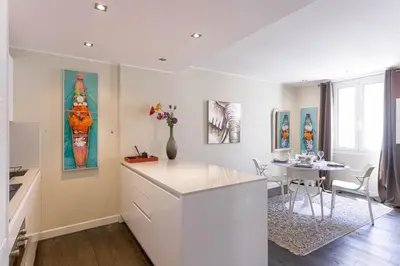 a white kitchen with a table and a dining room at Notre Dame - Terrace, AC, 3mn from Palais & Beach, modern in Cannes