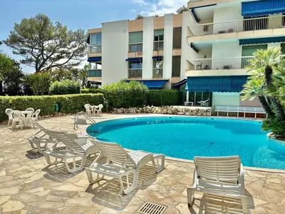 a swimming pool with chairs and a building at Eden Park in Cannes