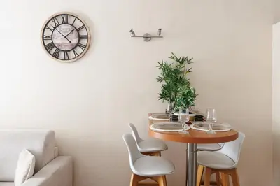 a dining room with a table and a clock on the wall at Immogroom - T2 - 10 min walk from Palais in Cannes