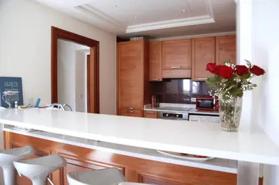 a kitchen with a white counter with a vase of red roses at FRGK OXFORD palace park in Cannes