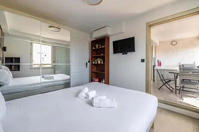 a bedroom with a large white bed and a dining room at L'ÉTOILE D'OR avec terrasse au centre de Cannes in Cannes