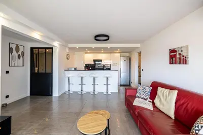 a living room with a red couch and a kitchen at L'ÉTOILE D'OR avec terrasse au centre de Cannes in Cannes