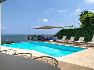 a swimming pool with chairs and an umbrella next to the ocean at Immogroom - Amazing Villa with sea view in Vallauris