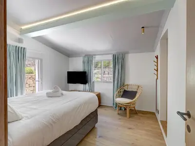 a bedroom with a large bed and a chair at Immogroom - Amazing Villa with sea view in Vallauris