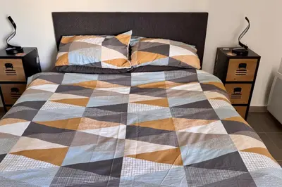a bed with a checkered blanket and two night stands at Charming 3 rooms located in Le Cannet near Cannes in Le Cannet