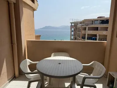 a table and chairs on a balcony with the ocean at Pierre Vacances VUE MER 748 in Cannes