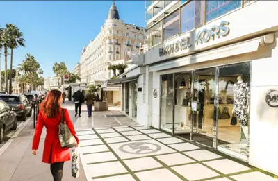 a woman walking down a sidewalk in front of a store at Cannes Banane in Cannes
