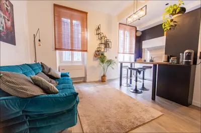 a living room with a blue couch and a table at LE COCON DE JAURÈS entre Gare Croisette et Palais in Cannes