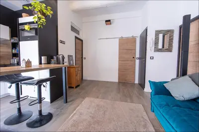 a living room with a blue couch and a desk at LE COCON DE JAURÈS entre Gare Croisette et Palais in Cannes