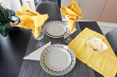 a table with two plates of food and yellow napkins at Duplex Charmant et Central Cannes Forville in Cannes