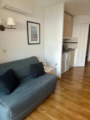 a living room with a blue couch and a kitchen at Renoir 252 - Appartement rez-de-jardin type F2 - Petite vue mer in Cannes