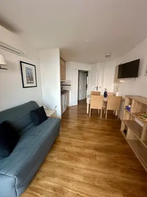a living room with a blue couch and a kitchen at Renoir 252 - Appartement rez-de-jardin type F2 - Petite vue mer in Cannes
