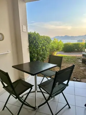 a table and chairs on a balcony with a view of the ocean at Renoir 252 - Appartement rez-de-jardin type F2 - Petite vue mer in Cannes