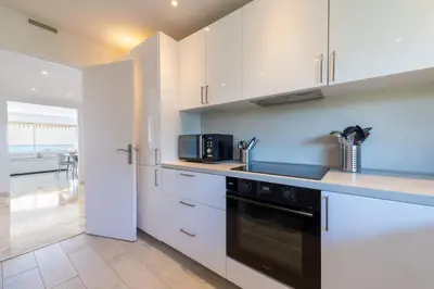 a kitchen with white cabinets and a black appliance at 2-Br Apartment Sea View & Pool Cannes Croix des Gardes in Cannes